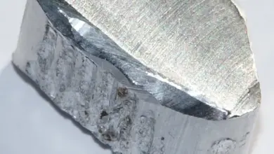 Bleskavý hliníkový slitek na bílém pozadí s viditelnou texturou řezu.