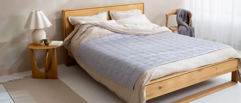 Postel s empatickou dekou na bílém povlečení.