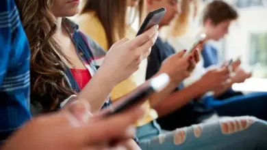 Skupina mladých lidí sedících a koukajících na své mobilní telefony.